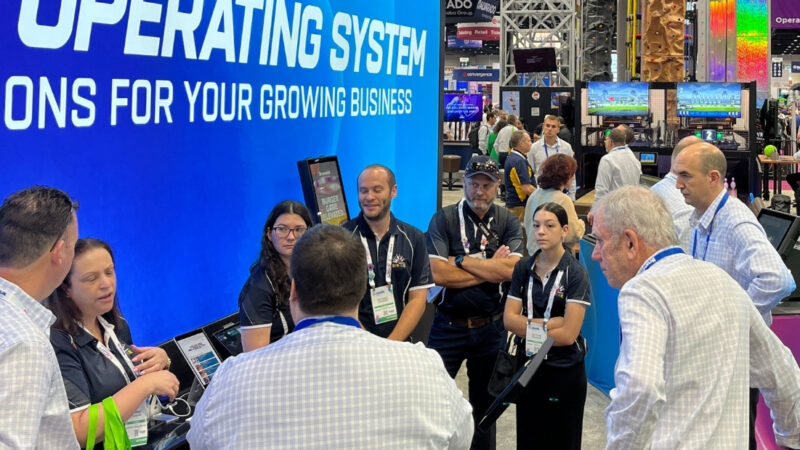 Group of people learning about a Brunswick Bowling Sync Service Kiosk at a trade show