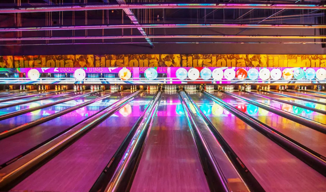 looking down multiple bowling lanes with colorful lighting